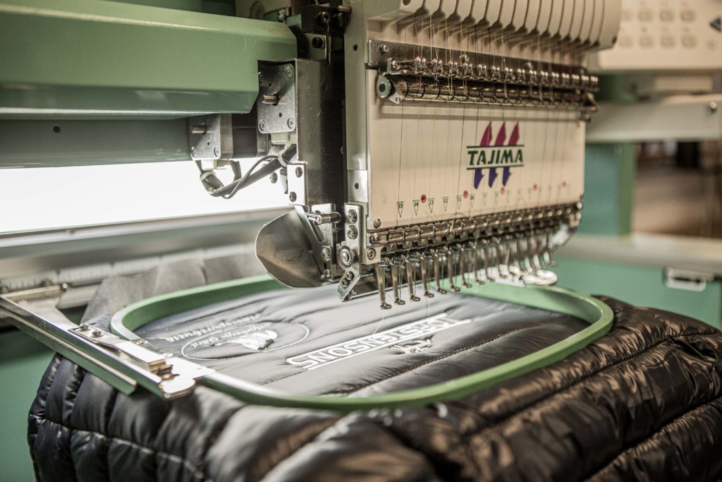 Brodyrmaskin som broderar en logga på en mörk jacka